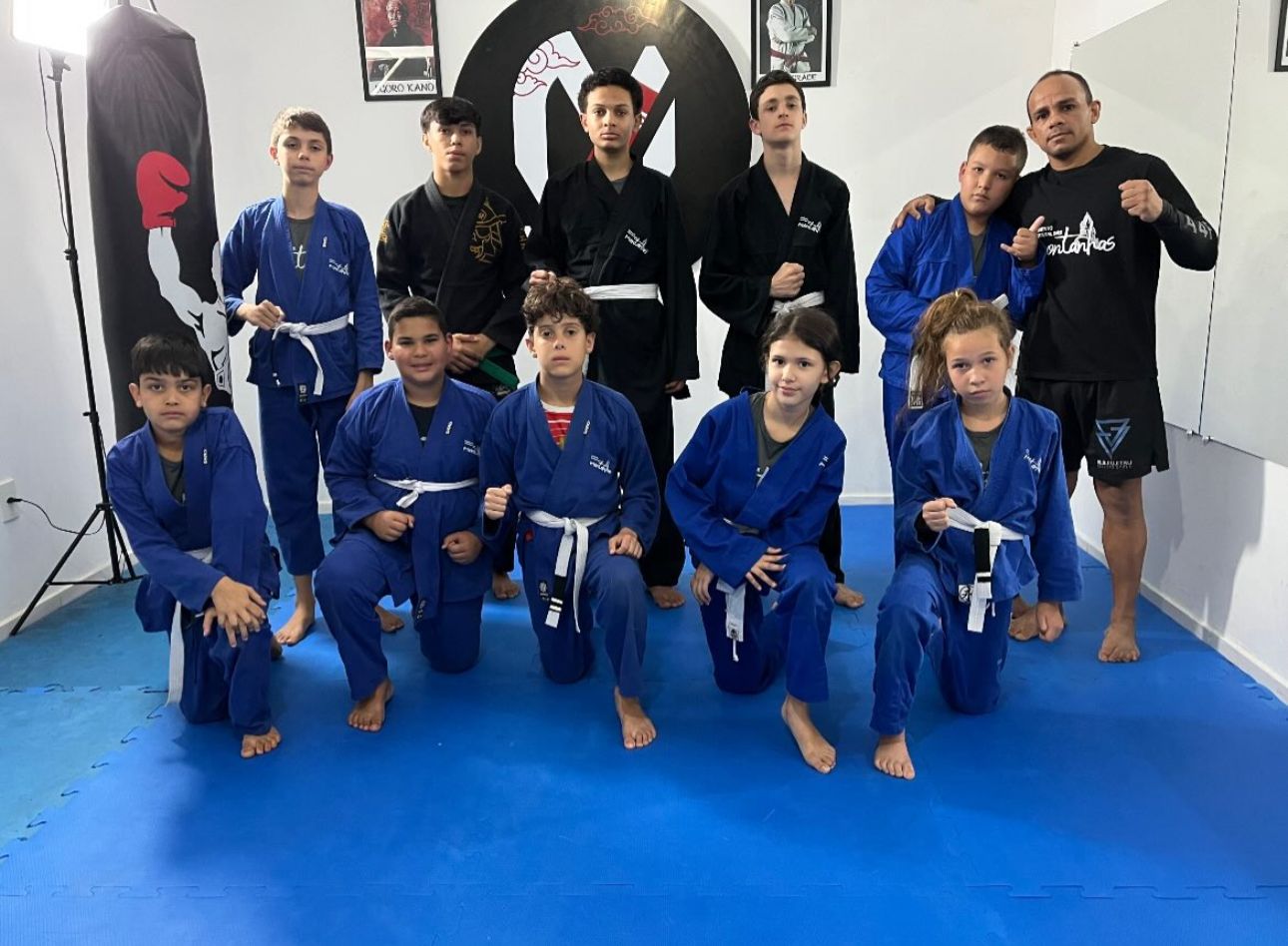 Turma de artes marciais com o professor no tatame do Centro de Treinamento