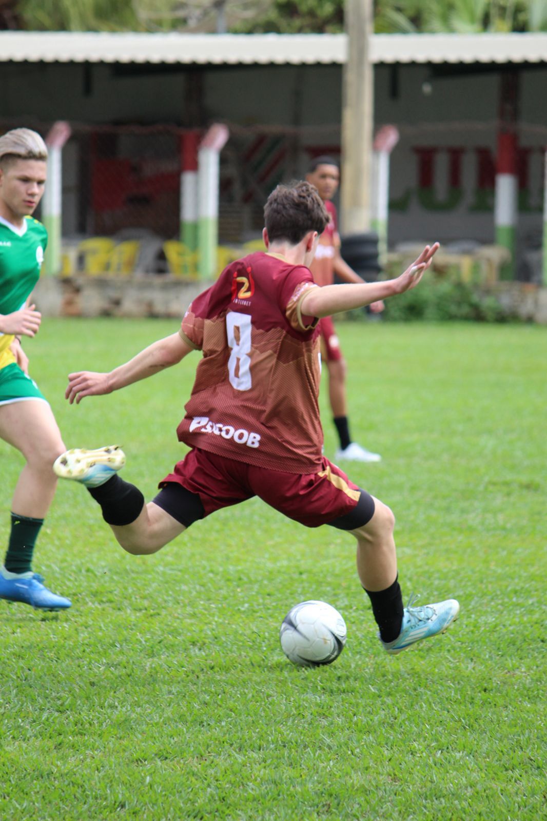 Jovem chutando a bola em jogo de futebol de campo